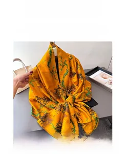 Detail of yellow silk scarf with green floral prints and satin texture for women
