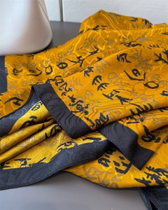 Detail of yellow silk scarf with black calligraphy and traditional Chinese cloud patterns