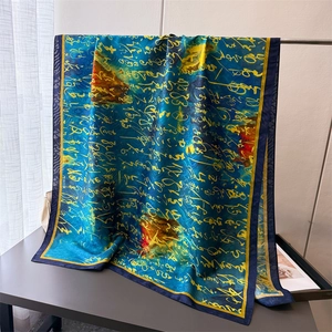 Detailed view of silk scarf with yellow calligraphy on dark blue fabric and soft draping
