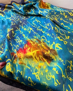 Detailed texture of dark blue silk scarf with yellow abstract calligraphy print