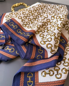 Macro detail of silk scarf with vintage gold horsebit chain patterns and soft folds