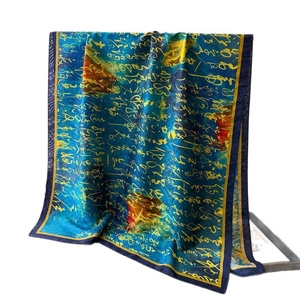 Elegant silk scarf with calligraphy print in navy and gold hanging on a metal rack