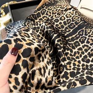 Macro view of leopard print silk scarf with luxury gold and brown texture details