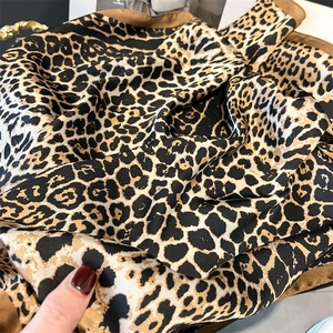 Close-up of leopard print silk scarf showing luxurious texture and refined brown hem
