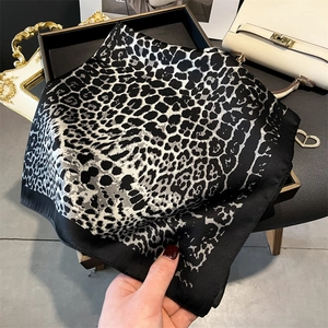 Leopard print faux silk square scarf in black and grey draped over a white handbag