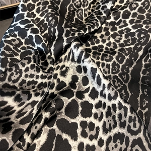 Close-up of black and white leopard print silk scarf with smooth satin texture
