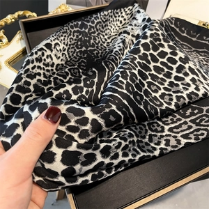 Detail view of leopard print silk scarf in a black gift box with satin texture