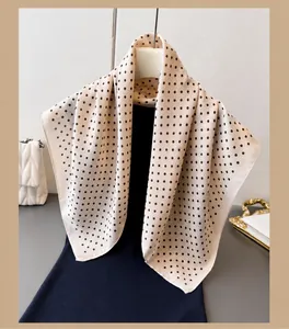 Detail van een beige zijden sjaal met bruine stippen gedrapeerd over kleding
