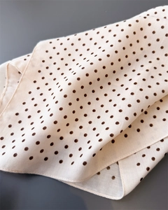 Detailopname van lichte gebroken witte polkadot sjaal met zijdeachtige textuur