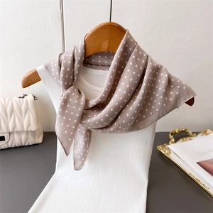 Detail van een elegante bruine sjaal met stippen geknoopt aan een hanger met tas