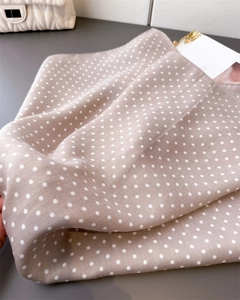 Detail van de zijdeachtige textuur van een beige sjaal met stippen in een lifestyle setting