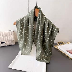 Elegante grijsgroene zijden sjaal met polkadots aan houten hanger met gebreide top