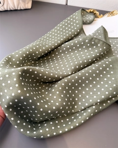 Detailopname van saliegroene polkadotsjaal met zachte keperstoftextuur en drapering