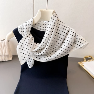 Detail van witte sjaal met zwarte stippen gecombineerd met een marineblauwe mouwloze top