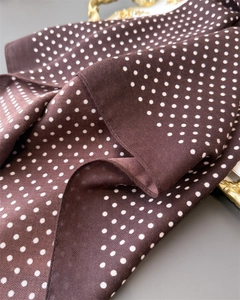 Detail van een bruine polkadot sjaal met visgraatmotief en zachte zijden textuur