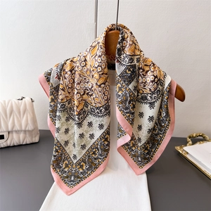 Elegant floral paisley silk scarf with pink border displayed on a wooden hanger