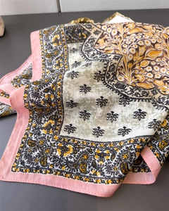 Detail of floral and paisley pattern on pink-edged square scarf with smooth texture