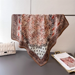 Close-up of vintage paisley flower silk scarf draped elegantly with a chain handbag