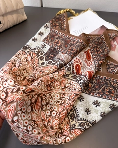 Detailed view of paisley floral silk scarf with earth tones on a stylish golden tray