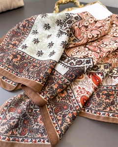 Detail of floral paisley pattern on silk scarf texture draped on a vintage gold tray