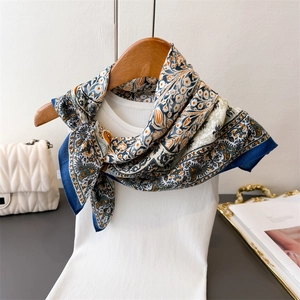 Detail of floral paisley silk-feel scarf draped elegantly over a white knitted sweater
