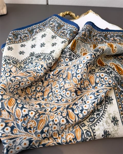 Close-up of floral paisley patterns on cream cotton-silk scarf with navy borders