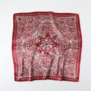 Vue détaillée du motif paisley rouge et blanc sur le tissu satiné du foulard carré