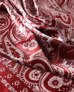 Détail macro du foulard en satin de soie rouge à motif cachemire avec texture brillante