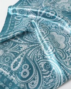 Gros plan du foulard en satin bleu avec motif paisley et texture soyeuse brillante