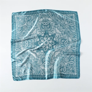 Détail d'un foulard carré en satin de soie avec motifs paisley bleu canard et blanc