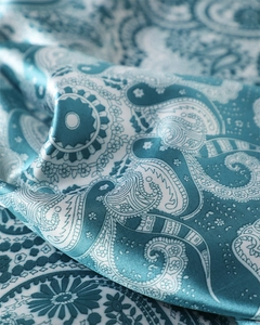 Détail macro du motif cachemire bleu sarcelle sur satin brillant avec éclat soyeux