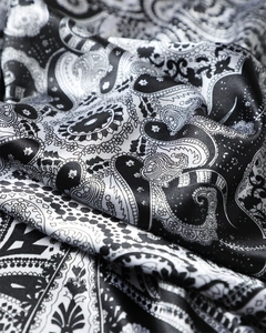 Gros plan du motif cachemire noir et blanc sur un foulard en satin soyeux