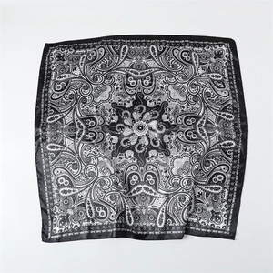 Détail du motif paisley monochrome sur un foulard carré en satin soyeux avec bordure noire