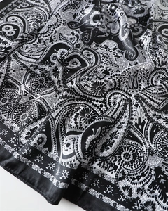 Détail du motif paisley sur foulard en satin noir et blanc avec reflet soyeux élégant