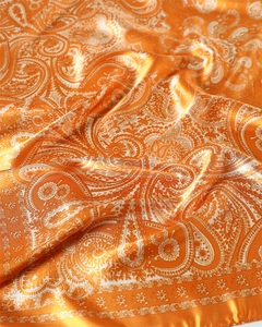 Gros plan sur un foulard en satin orange brillant avec motif cachemire et texture drapée