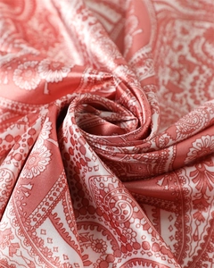 Gros plan d'un foulard en satin rose corail avec motifs paisley et texture soyeuse
