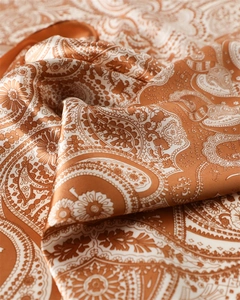 Détail de foulard en satin orange avec motif paisley élégant et texture soyeuse brillante