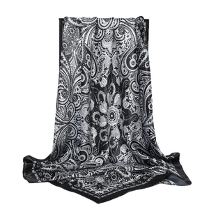 Élégant foulard en satin noir et blanc à motif paisley suspendu sur un support noir