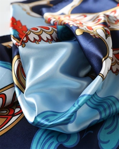 Dettaglio di un foulard in raso setoso con stampe paisley in blu, arancione e oro