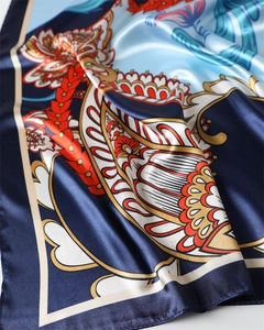 Dettaglio della sciarpa in raso con motivo paisley, bordi dorati e sfumature blu navy