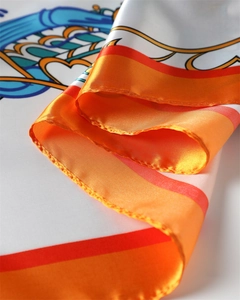 Dettaglio dei motivi a cuore e vite su un foulard di seta satinata arancione