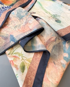 Detailed view of silk scarf fabric showing retro floral bird print and twill texture
