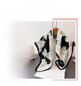 Detail of elegant black and white floral silk scarf with large camellia print on wooden hanger