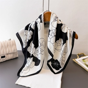 Elegant black and white camellia floral print scarf on a wooden hanger with luxury styling