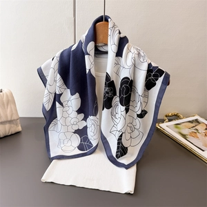 Elegant black and white camellia floral print silk scarf displayed on a white vest