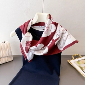 Detail of dark red floral silk scarf with white patterns draped over a mannequin