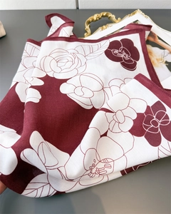 Detailed view of luxury silk scarf with large floral patterns on a golden tray