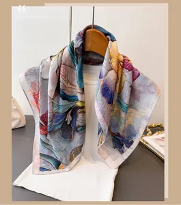 Close-up of floral silk scarf on a wooden hanger showing smooth texture and vibrant prints