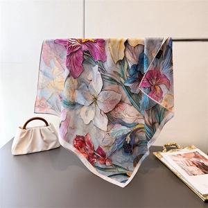 Luxurious square silk scarf with double-sided floral iris print hanging on a metal bar