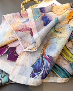 Detail of herringbone silk scarf with floral print on a luxury gold tray